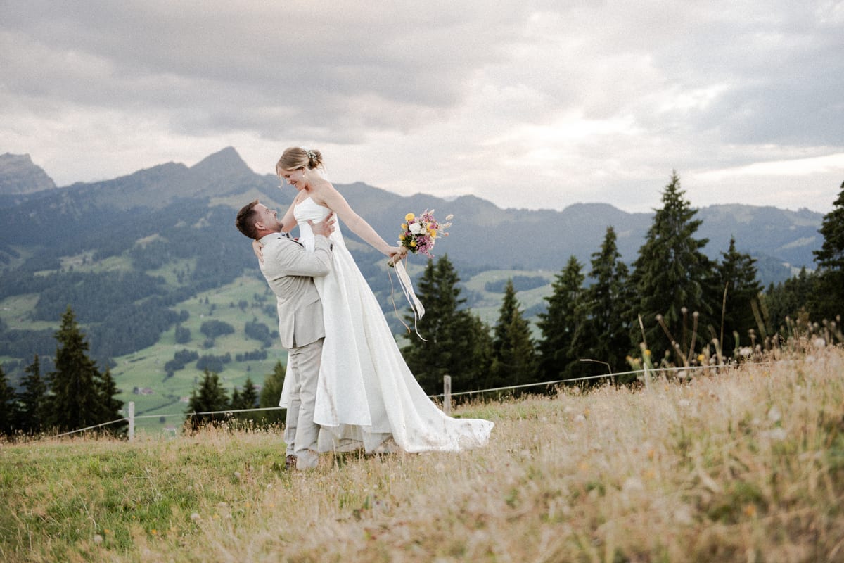 Brautpaar umarmt sich vor einer Berglandschaft